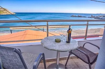a table with a bottle of wine and two glasses on a balcony at Haraki style studio in Haraki