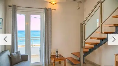 a living room with a staircase and a view of the ocean at Haraki style studio in Haraki