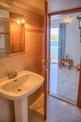 a bathroom with a sink and a shower and a door at Haraki style studio in Haraki