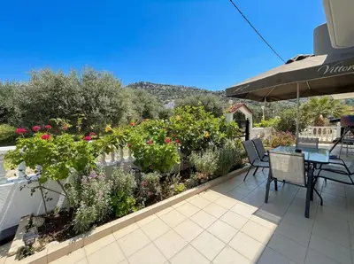 a patio with a table and chairs and flowers at Tharreni's house in Lindos in vlicha