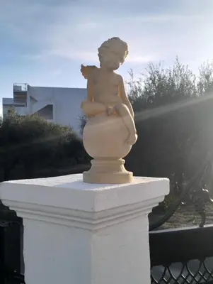 a statue of a little girl sitting on a ledge at Tharreni's house in Lindos in vlicha