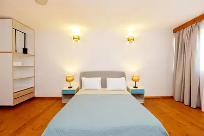 a bedroom with a bed and two lamps on two tables at Liri - Family paradise in Ialyssos