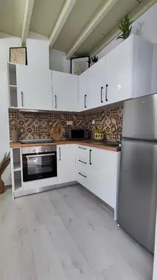 a kitchen with white cabinets and a stainless steel refrigerator at Luna Grande in Archangelos