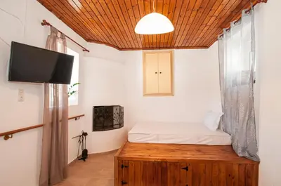 a room with a bed and a tv and a wooden ceiling at Giannis Place in Arnítha
