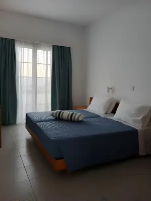 a bedroom with a bed with a blue comforter at Pefkos Crystal Bay SELF-CATERED Studios and Apartments in Pefki Rhodes