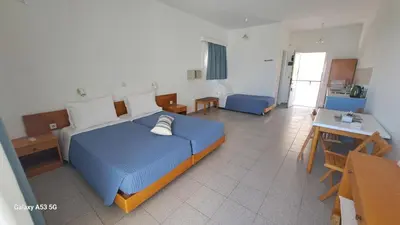 a bedroom with a bed with a blue comforter at Pefkos Crystal Bay SELF-CATERED Studios and Apartments in Pefki Rhodes