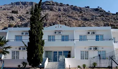 a white building with a mountain in the background at Pefkos Crystal Bay SELF-CATERED Studios and Apartments in Pefki Rhodes