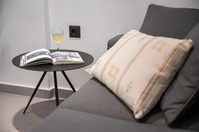 a pillow on a couch next to a table with a glass of wine at Rodos Downtown 107 in Rhodes Town