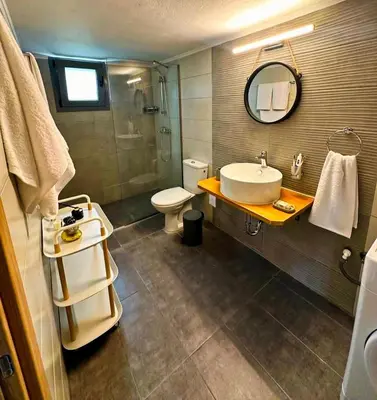 a bathroom with a sink and a toilet and a mirror at Arokaria Seaview House in Koskinou