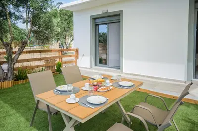 a wooden table and chairs in a yard at Arokaria Seaview House in Koskinou