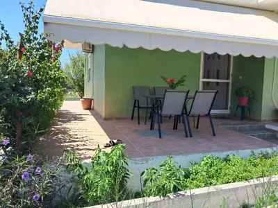 a patio with chairs and a table on a green house at Galinis Rooms in Paradeísion
