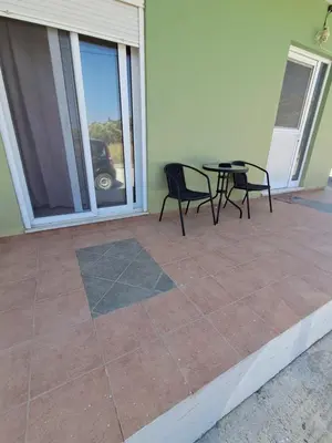 a patio with two chairs and a table and a window at Galinis Rooms in Paradeísion