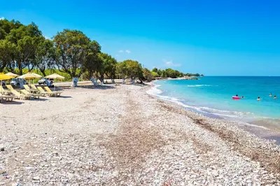 a beach with chairs and umbrellas and the ocean at Galinis Rooms in Paradeísion