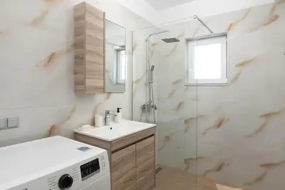 a bathroom with a shower and a sink and a washing machine at Irene Gem in Rhodes Town
