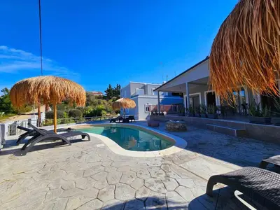 a swimming pool with two chairs and umbrellas at Dream Luxury Suites & Apartment Pastida in Pastida