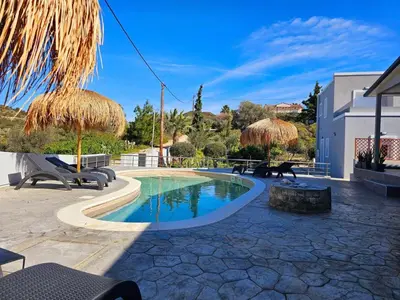 a swimming pool with chairs and umbrellas on a patio at Dream Luxury Suites & Apartment Pastida in Pastida