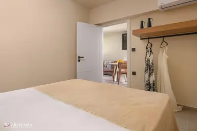 a bedroom with a bed and a dress hanging on a door at House Marigo Suites in Koskinou