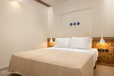 a bedroom with a large bed with white sheets at House Marigo Suites in Koskinou