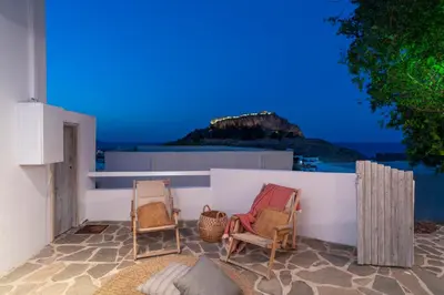 a patio with two chairs and a view of the ocean at Peaceful Lindos in Líndos