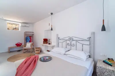 a bedroom with a large white bed and a chair at Peaceful Lindos in Líndos