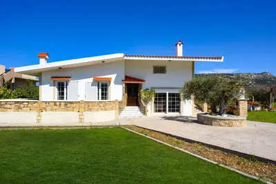 a white house with a green lawn in front of it at Yannis Place in Rhodes Town