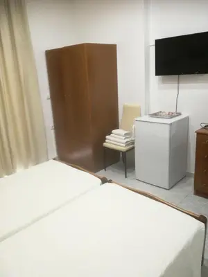 a bedroom with a bed and a tv and a chair at Hotel Dimitra Sun in Archangelos
