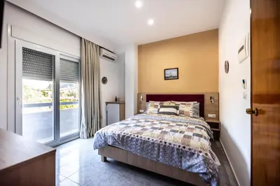 a bedroom with a bed and a large window at Hotel Dimitra Sun in Archangelos