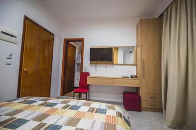 a bedroom with a bed and a desk and a cabinet at Hotel Dimitra Sun in Archangelos