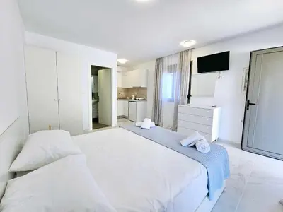 a large white bedroom with two beds and a tv at Dream Luxury Apartment Suites in Pastida