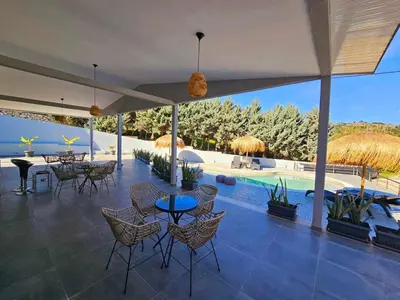a patio with tables and chairs and a swimming pool at Dream Luxury Apartment Suites in Pastida