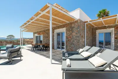 a patio with two beds and a table and chairs at Luxurious Villa with sea views in Gennadi Rhodes in Gennadi