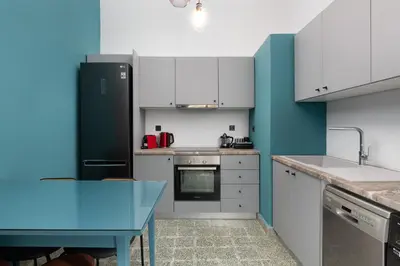 a kitchen with white cabinets and blue walls at Plumeria House in Rhodes Town