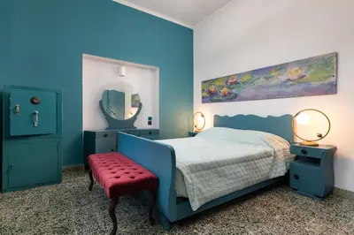 a blue bedroom with a bed and a red bench at Plumeria House in Rhodes Town