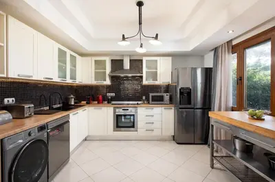 a kitchen with white cabinets and a stainless steel refrigerator at Dora 3 bedroom apartment in Rhodes Town