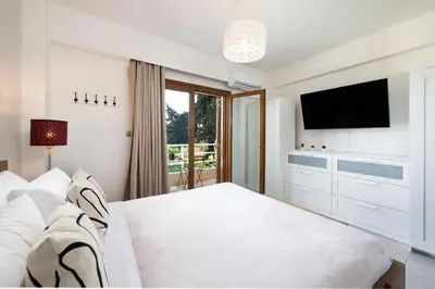 a bedroom with a white bed and a television at Dora 3 bedroom apartment in Rhodes Town