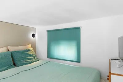 a bedroom with a bed with a blue window at Serene Ocean Haraki in Haraki