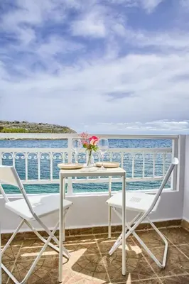 a table and two chairs on a balcony with the ocean at Serene Ocean Haraki in Haraki
