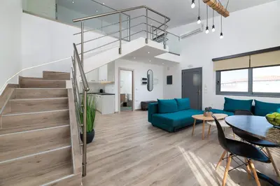 a living room with a staircase and a blue couch at Stone Apartments in Kremasti