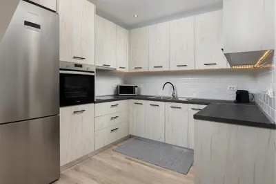 a kitchen with white cabinets and a stainless steel refrigerator at Stone Apartments in Kremasti