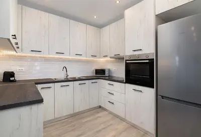 a kitchen with white cabinets and a stainless steel refrigerator at Stone Apartments in Kremasti