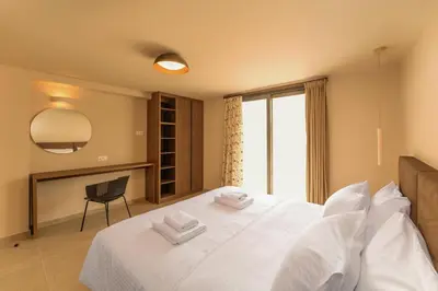 a bedroom with a white bed with a chair and a window at Luma Villas in Rhodes Town