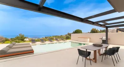 an outdoor patio with a table and chairs and a swimming pool at Luma Villas in Rhodes Town