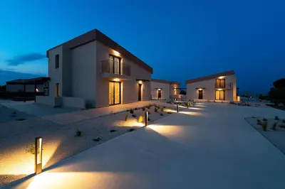 a building with lights on the beach at night at Luma Villas in Rhodes Town