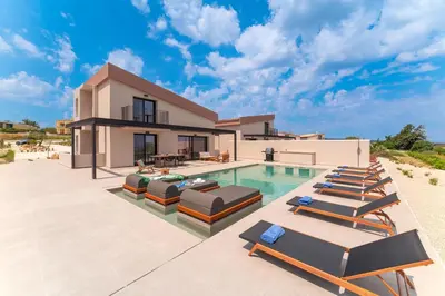 a villa with a swimming pool and lounge chairs at Luma Villas in Rhodes Town