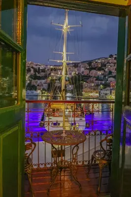 a table and chairs on a balcony with a ship at 