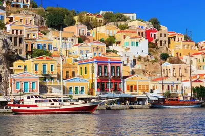 a group of colorful houses on a hill with a boat at 