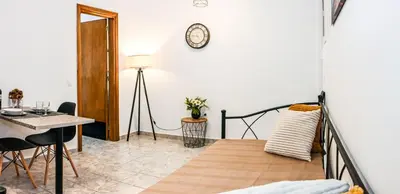 a living room with a table and a clock on the wall at Casa 30 House Complex Center of Ialysos in Ialyssos