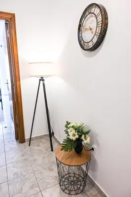 a clock on a wall next to a table with flowers at Casa 30 House Complex Center of Ialysos in Ialyssos