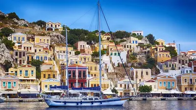 a boat in a harbor with houses on a hill at 