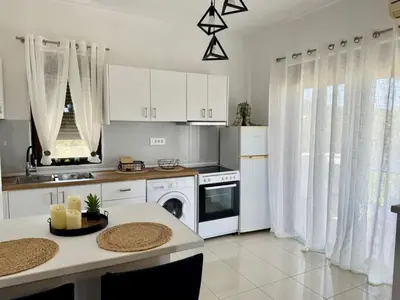 a kitchen with white cabinets and a table with chairs at Papas house 2 near Faliraki kalithies in Kalithies